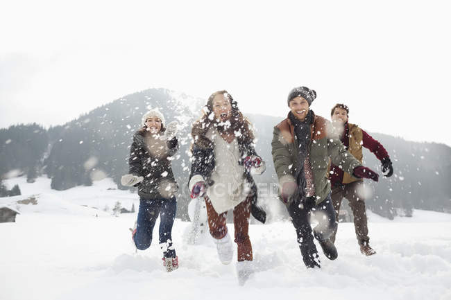 Happy friends playing in snowy field — Stock Photo