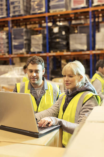 Workers using laptop in warehouse — Stock Photo