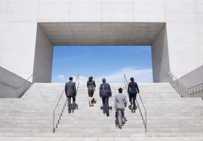 Business people ascending modern stairs — Stock Photo