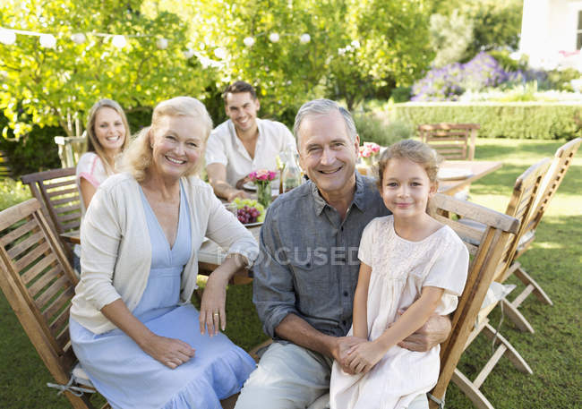 Familia feliz sonriendo en la mesa al aire libre - foto de stock