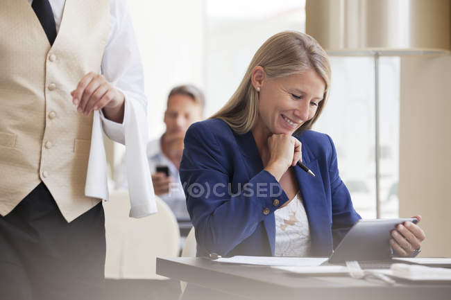 Businesswoman working with digital tablet in restaurant — Stock Photo