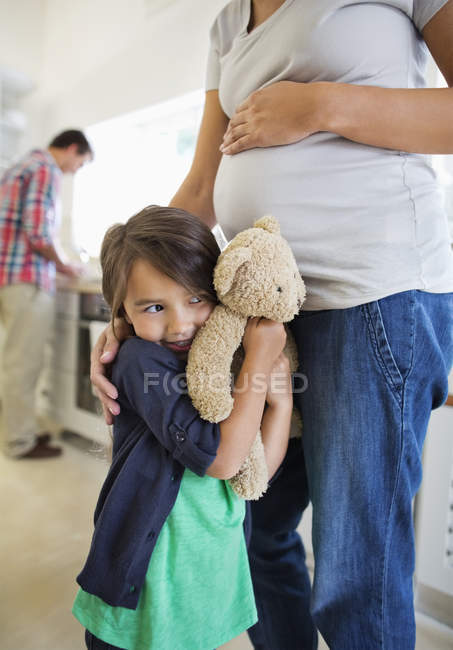 Girl hiding behind pregnant mother — Stock Photo