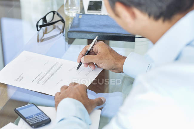 Businessman making notes at desk at modern office — Stock Photo
