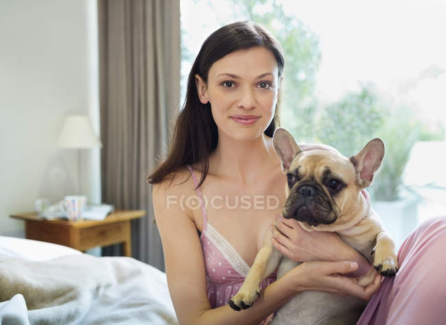 Woman petting dog in bed at modern home — Stock Photo