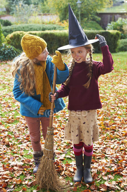 Девушки играют с ведьминой шляпой и метлой на открытом воздухе — стоковое фото