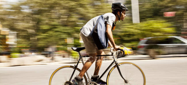 Side view of man riding bicycle on city street — Stock Photo
