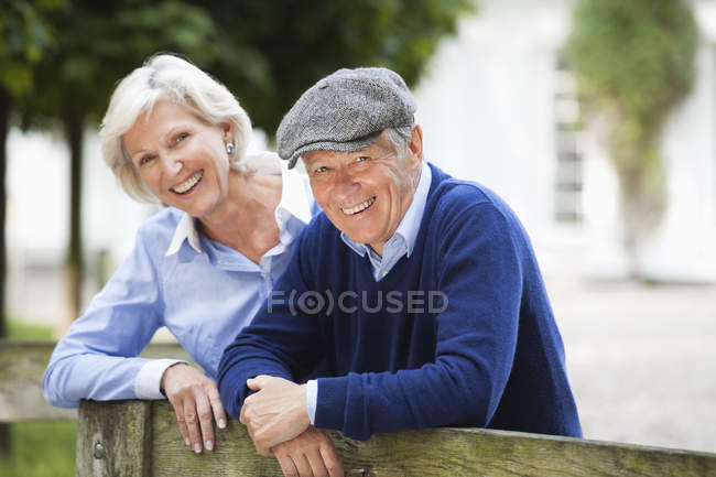 Couple smiling by wooden fence — Stock Photo