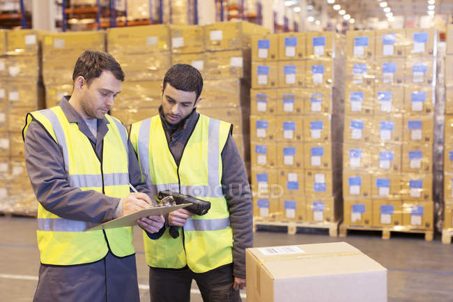 Workers writing on clipboard in warehouse — Stock Photo