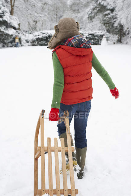 Visão traseira da mulher puxando trenó de madeira na neve — Fotografia de Stock
