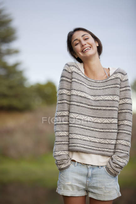 Portrait of smiling woman with hands in short pockets — Stock Photo