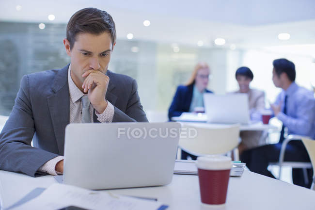 Businessman working on laptop at table in modern office building — Stock Photo