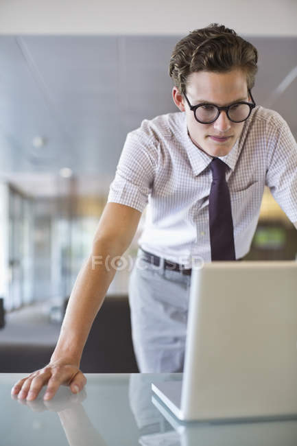 Businessman working on laptop at desk at modern office — Stock Photo