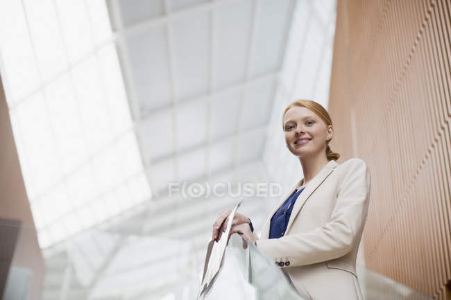 Retrato de la mujer de negocios sonriente sosteniendo informe en la oficina moderna - foto de stock