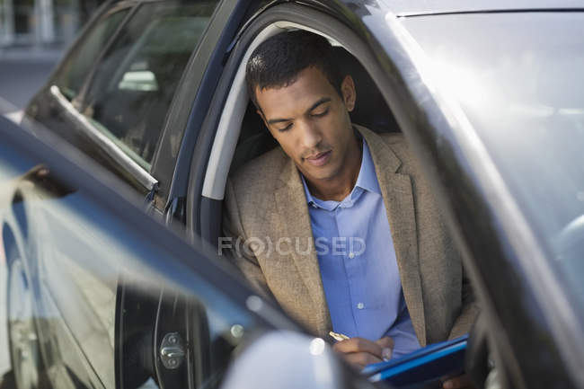 Joven negro hombre de negocios trabajando en coche - foto de stock