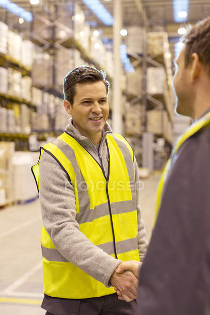 Workers shaking hands in warehouse — Stock Photo
