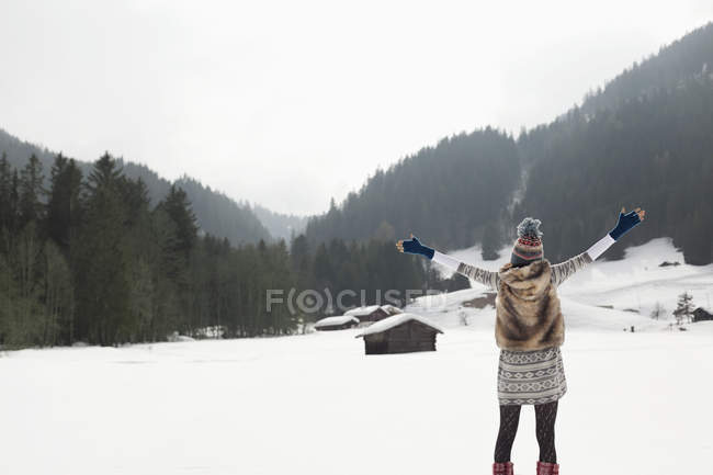 Mulher despreocupada com os braços estendidos no campo nevado — Fotografia de Stock