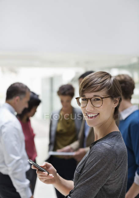 Geschäftsfrau benutzt Handy bei Besprechung in modernem Büro — Stockfoto