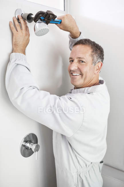 Encanador caucasiano hábil trabalhando na cabeça do chuveiro no banheiro — Fotografia de Stock