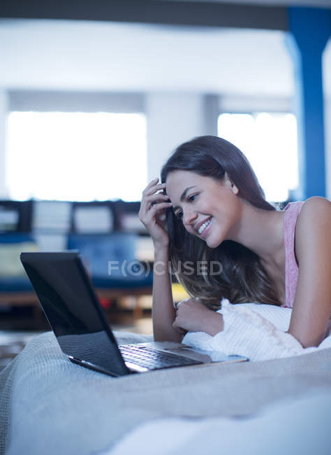 Жінка використовує ноутбук на ліжку — стокове фото