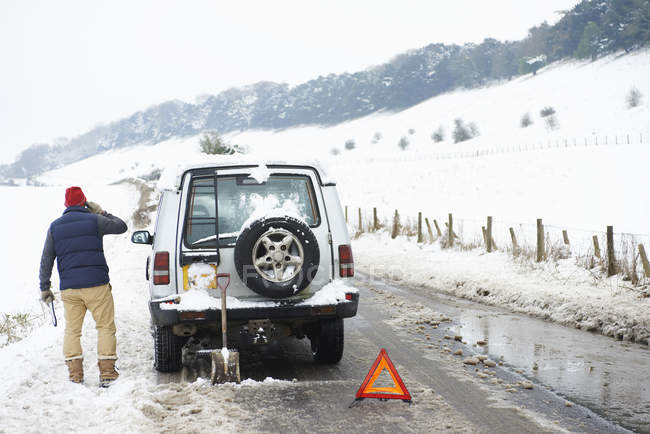 Uomo che lavora su auto guasta nella neve — Foto stock