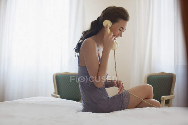 Mujer sonriente en camisón hablando por teléfono - foto de stock