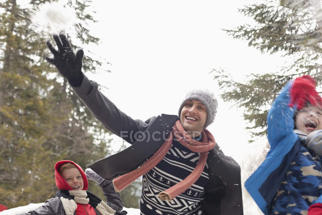 Padre juguetón e hijos lanzando nieve - foto de stock