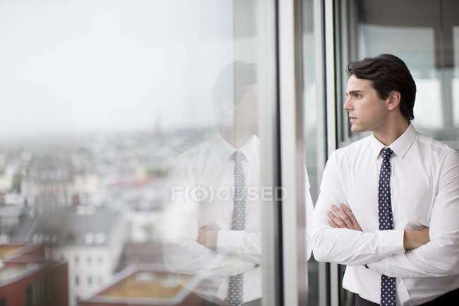 Businessman looking at modern office window — Stock Photo