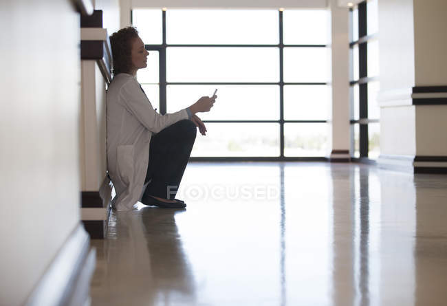 Doctor using cell phone in hospital hallway — Stock Photo