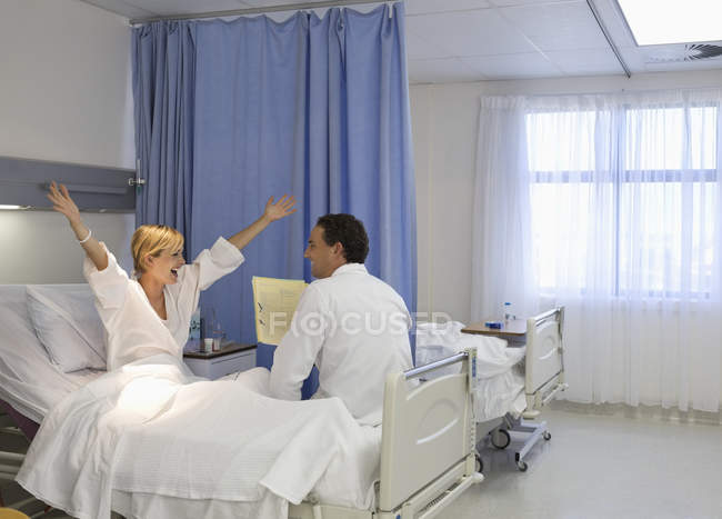 Doctor hablando con animar al paciente en la habitación del hospital - foto de stock
