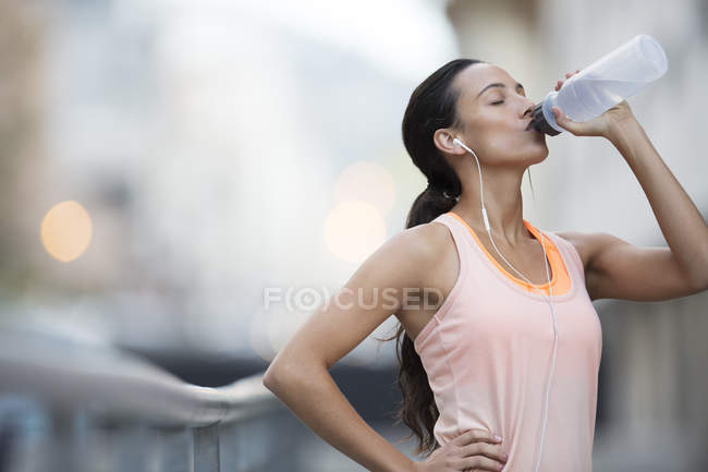 Woman drinking water after exercising on city street — Stock Photo