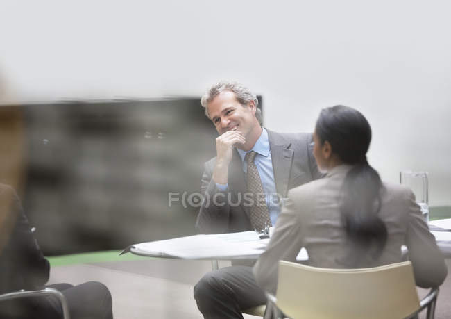 Hombre de negocios sonriente en la reunión en la oficina moderna - foto de stock