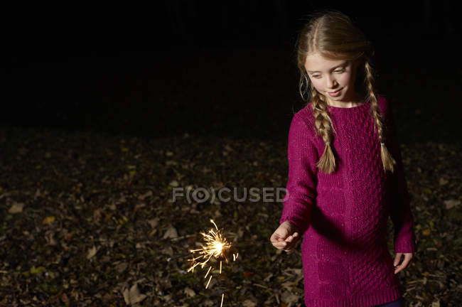 Girl playing with sparkler outdoors at night — Stock Photo