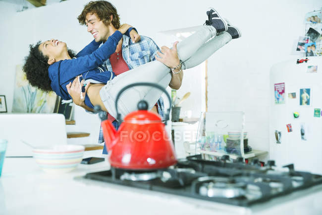 Молодая счастливая пара играет вместе на кухне — стоковое фото