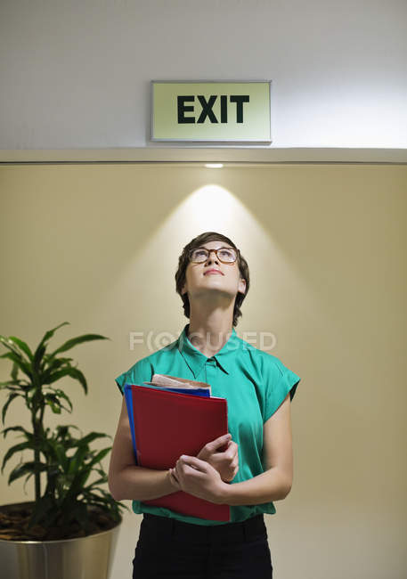 Femme d'affaires debout sous panneau de sortie de bureau au bureau moderne — Photo de stock