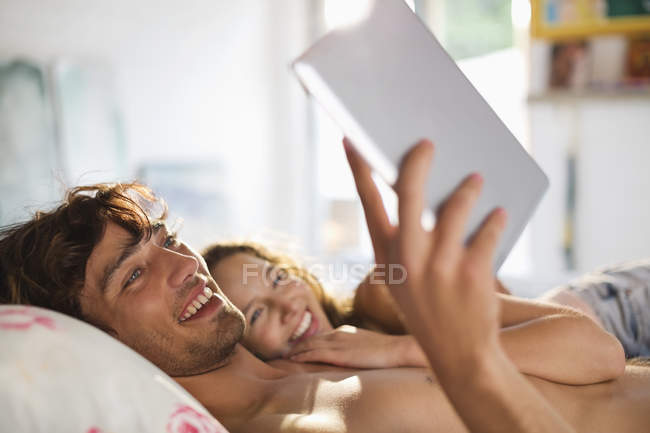 Casal usando computador tablet na cama — Fotografia de Stock