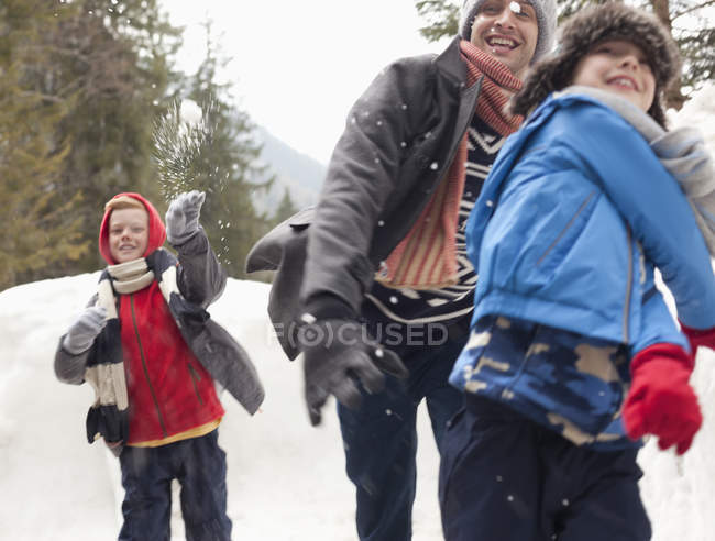 Padre e hijos disfrutando de la pelea bola de nieve - foto de stock