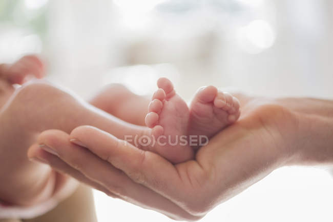 Madre acunando los pies del bebé recién nacido - foto de stock
