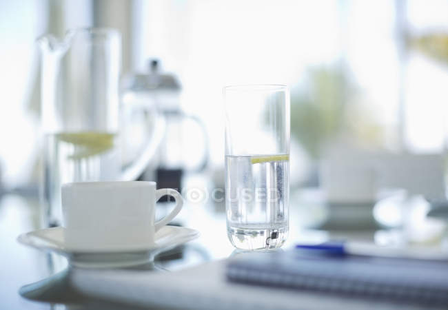 Tazas de café y vasos de agua en la mesa de reunión - foto de stock
