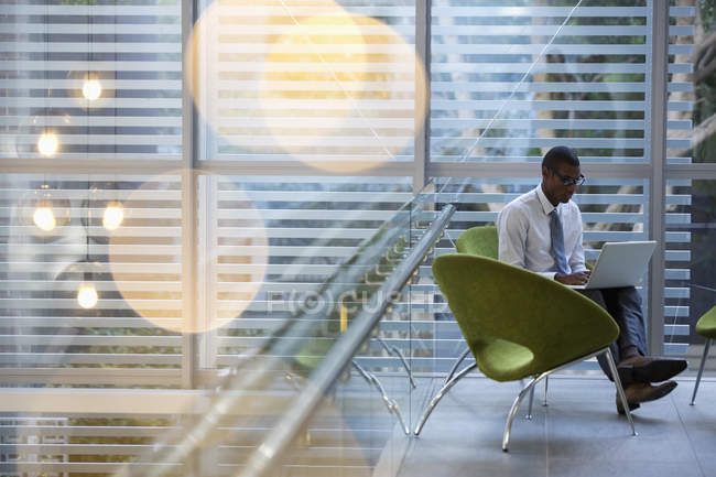Empresário usando laptop no lobby no escritório moderno — Fotografia de Stock