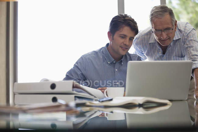 Older man and younger man working together at desk — Stock Photo
