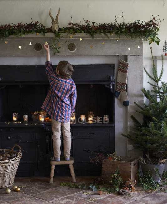 Boy decorating Christmas fireplace — Stock Photo