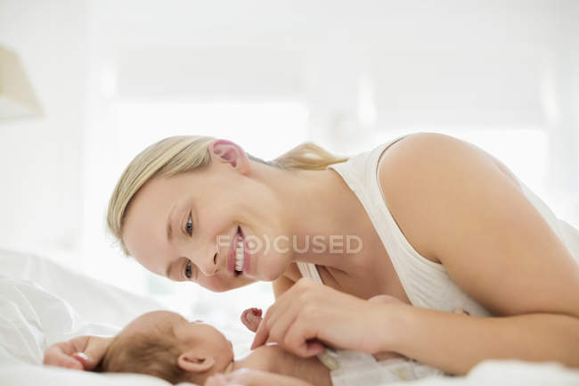 Mother cradling newborn infant on bed — Stock Photo