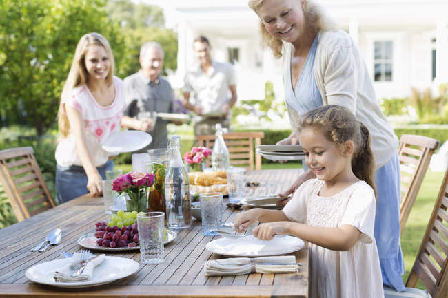 Happy family setting table outdoors — Stock Photo