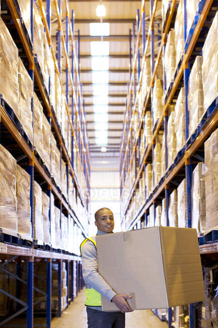 Trabalhador transportando caixa no armazém — Fotografia de Stock
