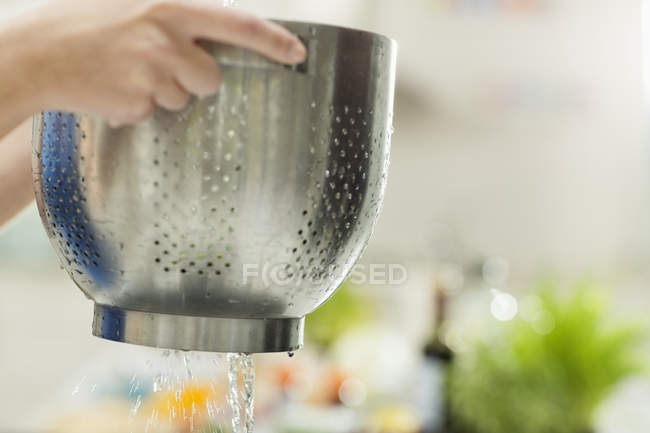 Mujer colando comida en la cocina - foto de stock