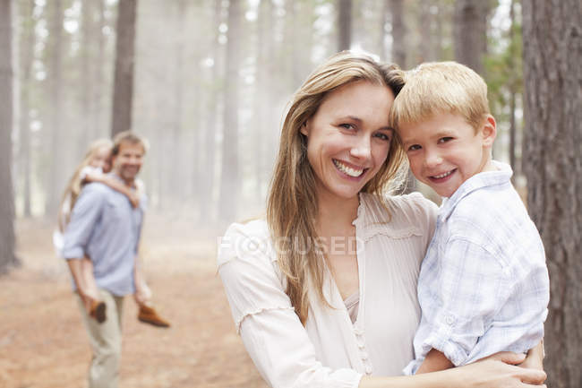 Retrato de mãe sorridente segurando filho na floresta — Fotografia de Stock