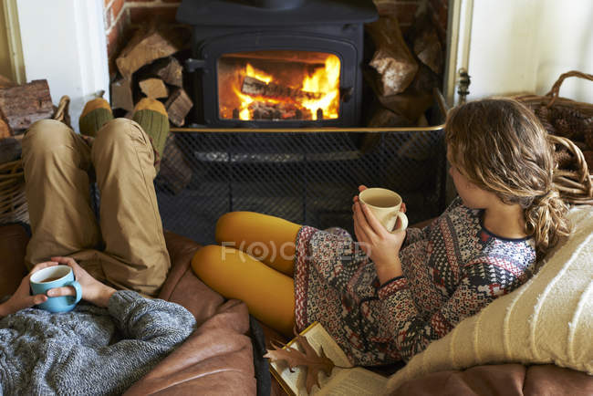 Children drinking cups of tea by fire — Stock Photo