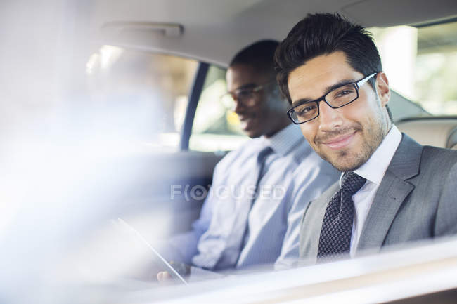 Businessman using digital tablet in car back seat — Stock Photo