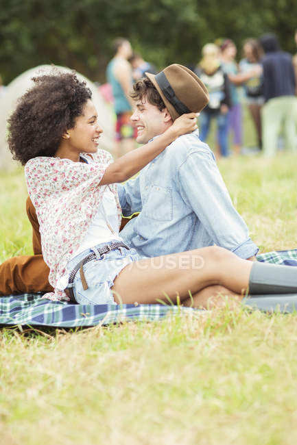 Pareja abrazándose en la manta en la hierba en el festival de música - foto de stock