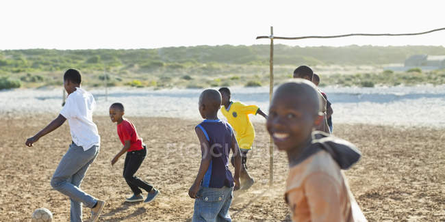 Chicos jugando fútbol juntos en el campo de tierra - foto de stock